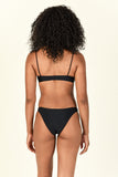 Model standing to the back wearing the Muse Scoop Top and Most Wanted Bottom in Black