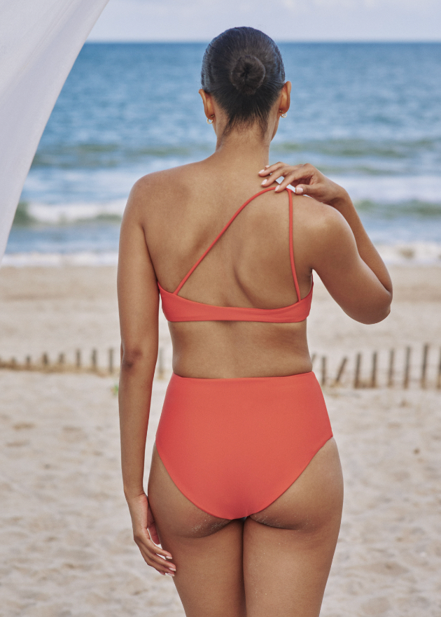 Model on the beach showing the back of the Apex Top and Bound Bottom in Clay