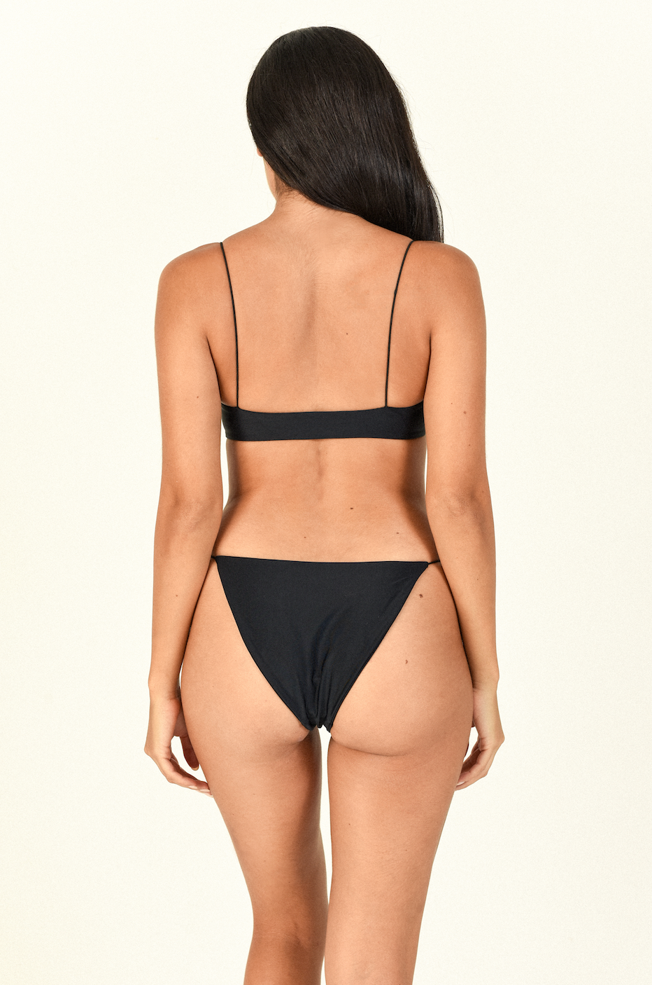 Model standing backwards while wearing the Micro Muse Scoop Top and Micro Bare Minimum Bottom in Black
