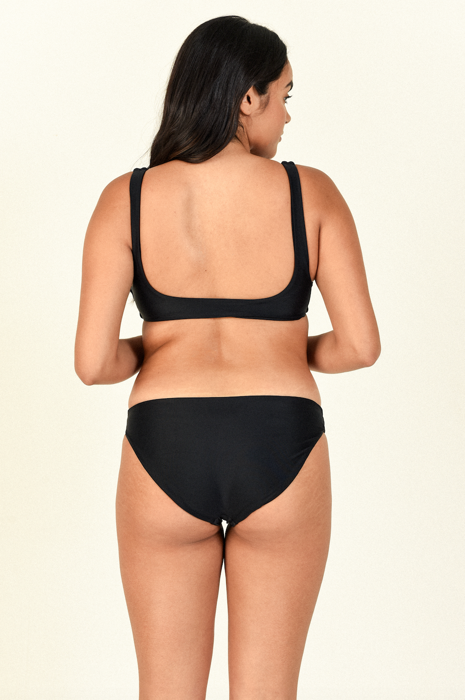 Model standing to the back to the side wearing the Rounded Edges Top and Most Wanted Bottom in Black